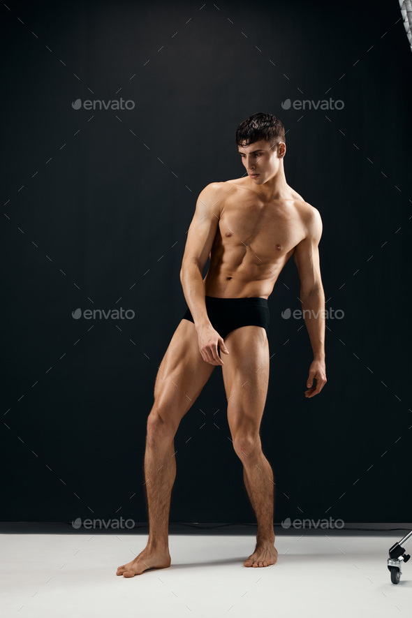 Man With A Pumped Up Naked Body In Black Panties Posing Against A Dark