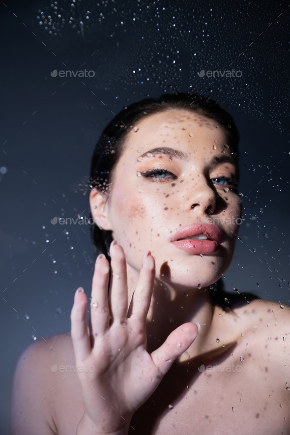 Sexy Model With Naked Shoulders Touching Wet Glass On Grey Background