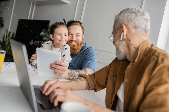 Smiling Gay Man Hugging Daughter And Holding Digital Tablet Near