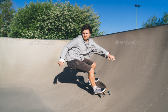 Sportsman Riding Skateboard On Ramp At Skate Park Practicing Tricks