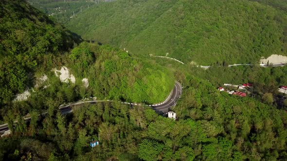 Aerial View Of A Curved Winding Road Trough The Mountains With Green