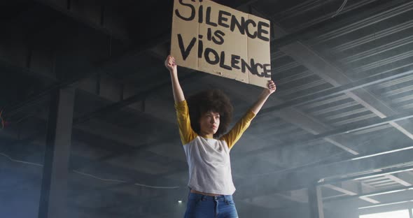 Portrait of african american woman holding protest placard in empty parking garage alt