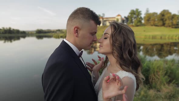 Caucasian Groom with Bride in the Park Near Lake. Wedding Couple. Newlyweds Kiss alt