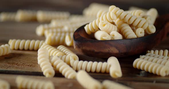 The Dry Fusilli Pasta on the Table and Spoon Rotates Slowly.  alt
