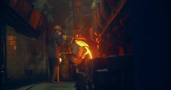 Foundry, a man pours molten metal into the mold