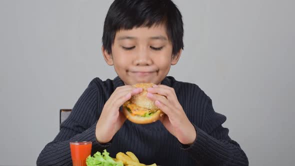 Cute Asian boy eating a delicious hamburger