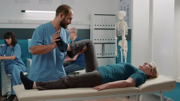 Male Physician Doing Legs Raise Procedure with Senior Patient alt