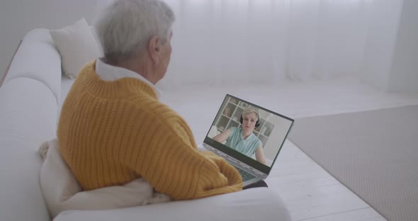 Elderly Man Is Communicating with His Adult Daughter By Video Call at Screen of Notebook, Sitting on alt