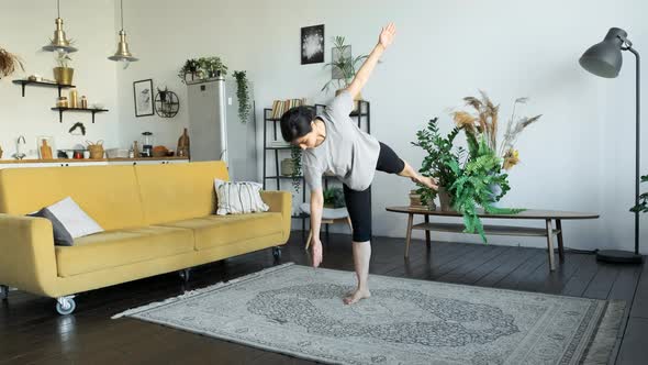 A Young Indian Woman Does Yoga Meditation At Home, Does A Balance Exercise, Stands On One Leg alt