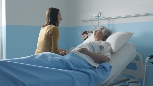 Woman visiting her senior mother at the hospital and talking with her