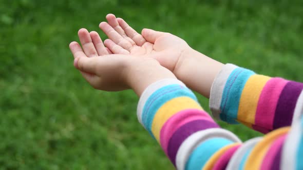 Small child hands catch raindrops into palms of hands closeup 