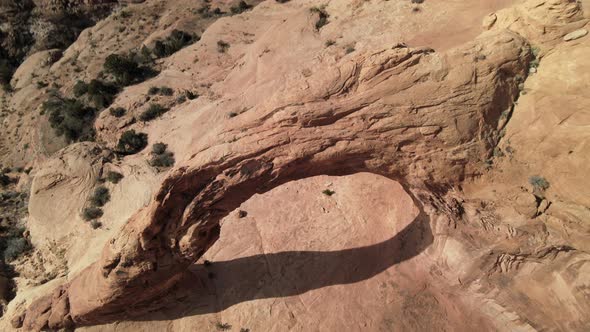 Aerial drone views as the camera tilts around Corona Arch, west of Moab, Utah. alt