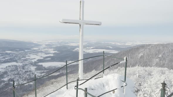 A Cross at a Lookout with a View on a Snowcovered Mountainous Winter Landscape alt