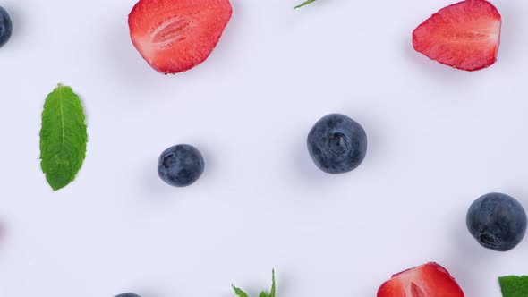 A Rotating Background of Blueberries Strawberries and Mint Leaves on a White Background the Concept