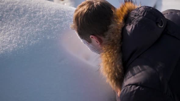 A Man in a Winter Jacket Makes an Imprint of His Face in a Snowdrift alt