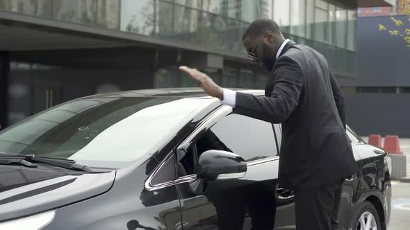 Scrupulous Afro-American Man Wiping His New Car Before Leaving Parking Lot alt