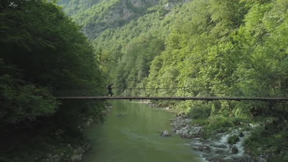 Aerial view of woman traveler walking on the bridge under Tara river in Montenegro alt