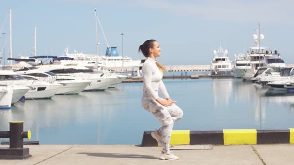 Sportive Woman Training Outdoors Doing Crossfit Exercise By the Ocean Pier.