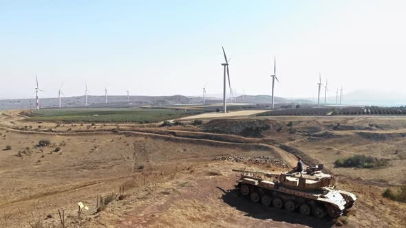 adult man meditating on deserted tank in front windmill farm landscape