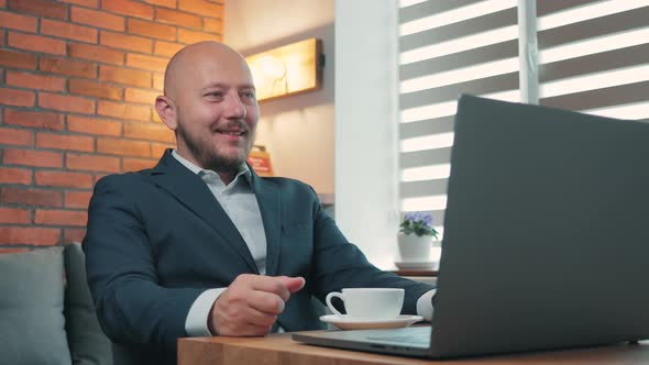 Smiling man in the suit have video call on a laptop at home office