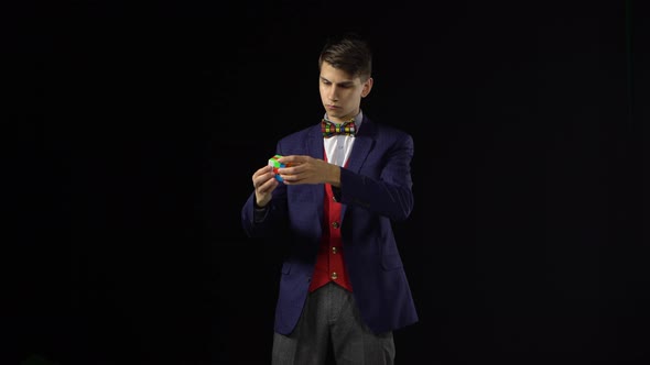 Brunette Man in Suit Is Solving Rubik's Cube in Dark. alt