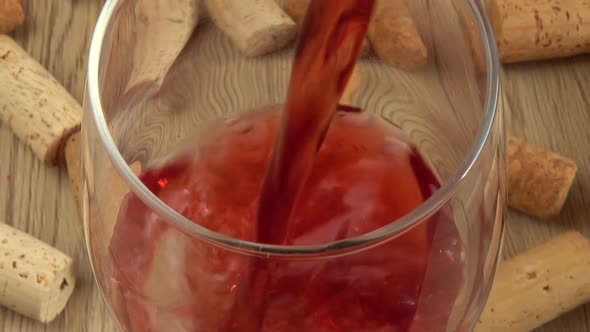 Wine is poured into a glass on the background of wine corks. alt