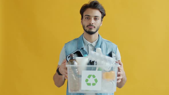 Portrait of Indian Man Holding Box of Plastic Waste for Recycling and Looking at Camera alt