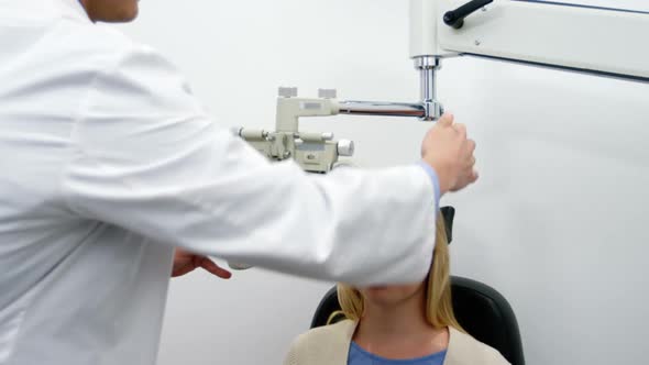 Smiling optometrist examining female patient on phoropter alt
