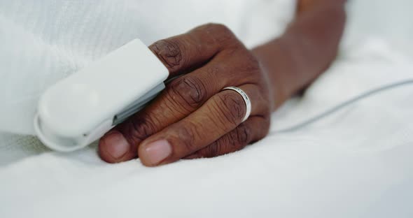 Close-up of pulse oximetry on African american male patient hand in the ward at hospital alt