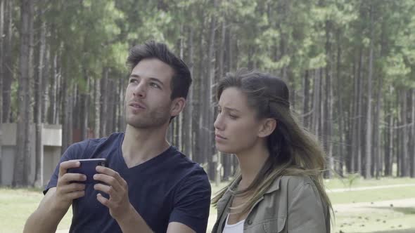 Couple using smart phone to navigate in woods alt