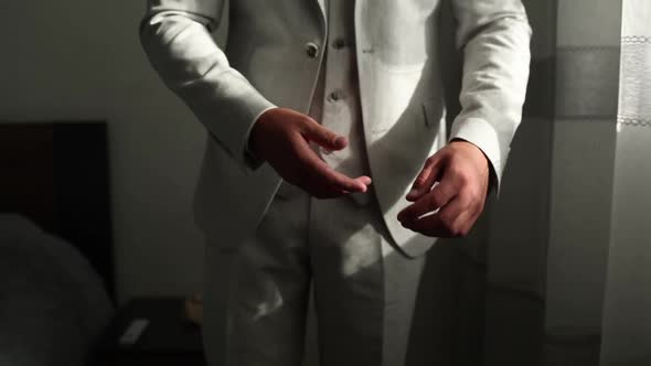 man fastening the button of his suit jacket