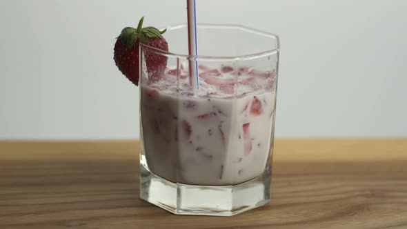 Someone Drinks Strawberry Milk From a Glass with Tubule, Preparing Fruit Cocktail in Home Kitchen alt