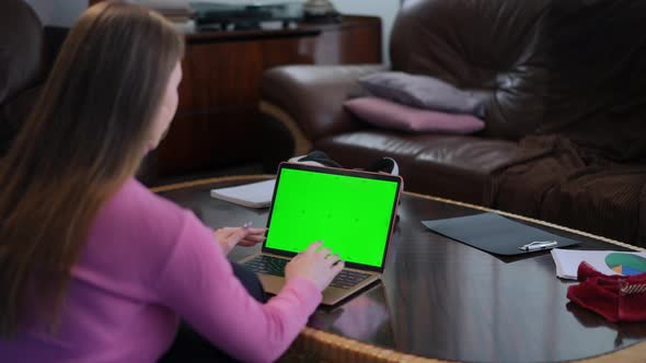 Blurred Young Woman Sitting on the Left Typing on Green Screen Laptop Keyboard alt