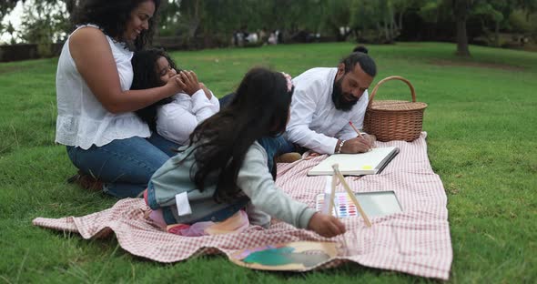 Indian parents having fun at city park painting with their children alt