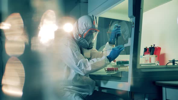 Expert in a Hazmat Suit Is Using a Pipette To Work with Probes alt