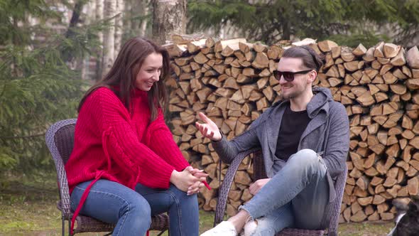 Young Couple Have Fun on Picnic, Girl and Guy Sits By Campfire Chatting Outdoors