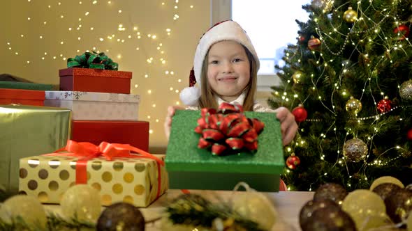 67Yearold Girl Wearing a Santa Hat Against the Background of a Christmas Tree and Bright Boxes with alt