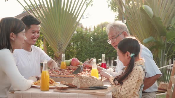 Asian retirement grandfather, pretty granddaughter, and parents enjoying eating pizza together alt