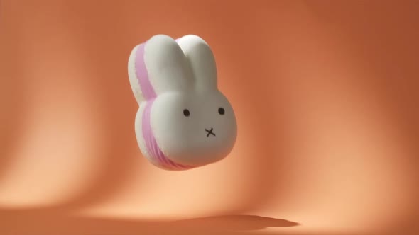 Big White and Pink Spongy Rabbit Falling Down on the Orange Background in Slow Motion