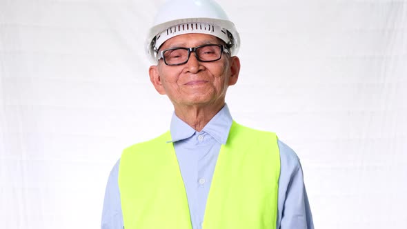 Confident senior engineering architect wearing vest and helmet on white background in studio. alt