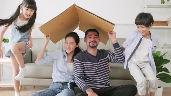 Asian family played in living room and built cardboard house with imagination. alt