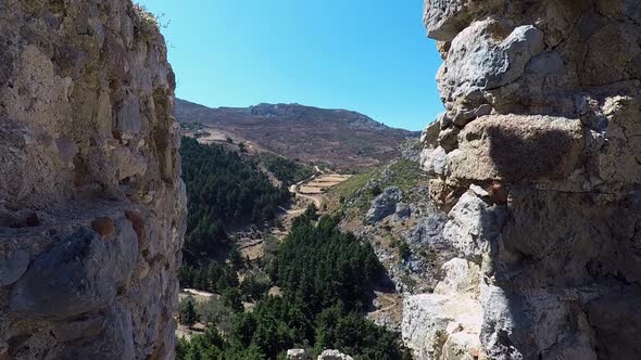 Looking through a gap in the wall of the castle ruins of Paleo Pili an historical site on the island alt