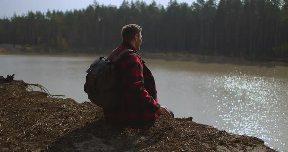 Man With Backpack Comes Sits at The Lake Bank Man Silhouette Wild Duck Swan Is Swimming at The Lake alt
