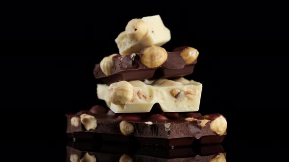 chocolate black and white with nuts. Chocolate bar on black background rotation alt