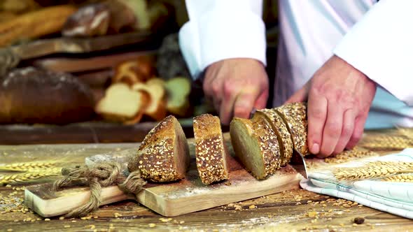 A baker at a Bakery Cuts a Baguette Into Several Pieces alt