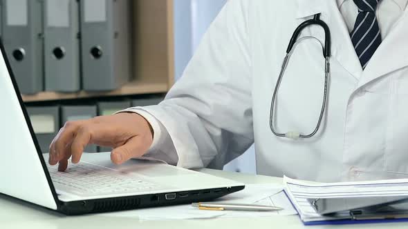 Professional Pulmonologist Typing on Laptop and Looking at Lungs X-Ray, Close-Up alt