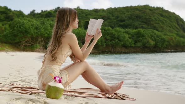 Asian woman relaxing, sunbathing, reading, drinking coconut water On the beach