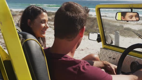 Happy caucasian couple sitting in beach buggy by the sea talking alt