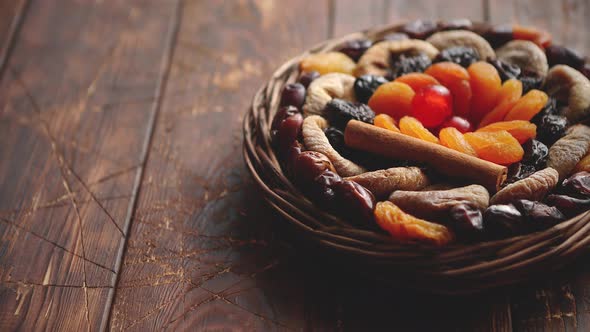Mix of Dried Fruits in a Small Wicker Basket on Wooden Table alt