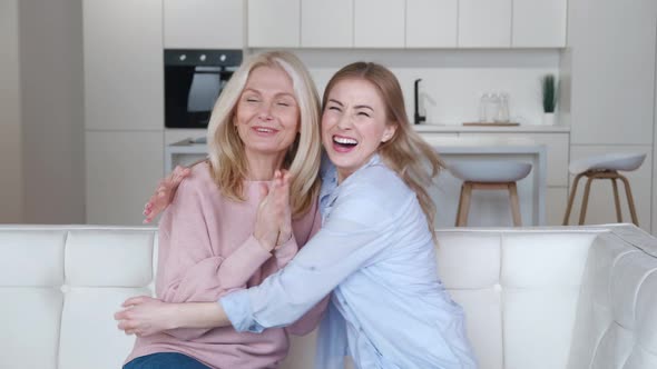 Surprised Happy Adult Daughter and Her Senior Mom Rejoicing Success Win While Sitting on Couch at alt